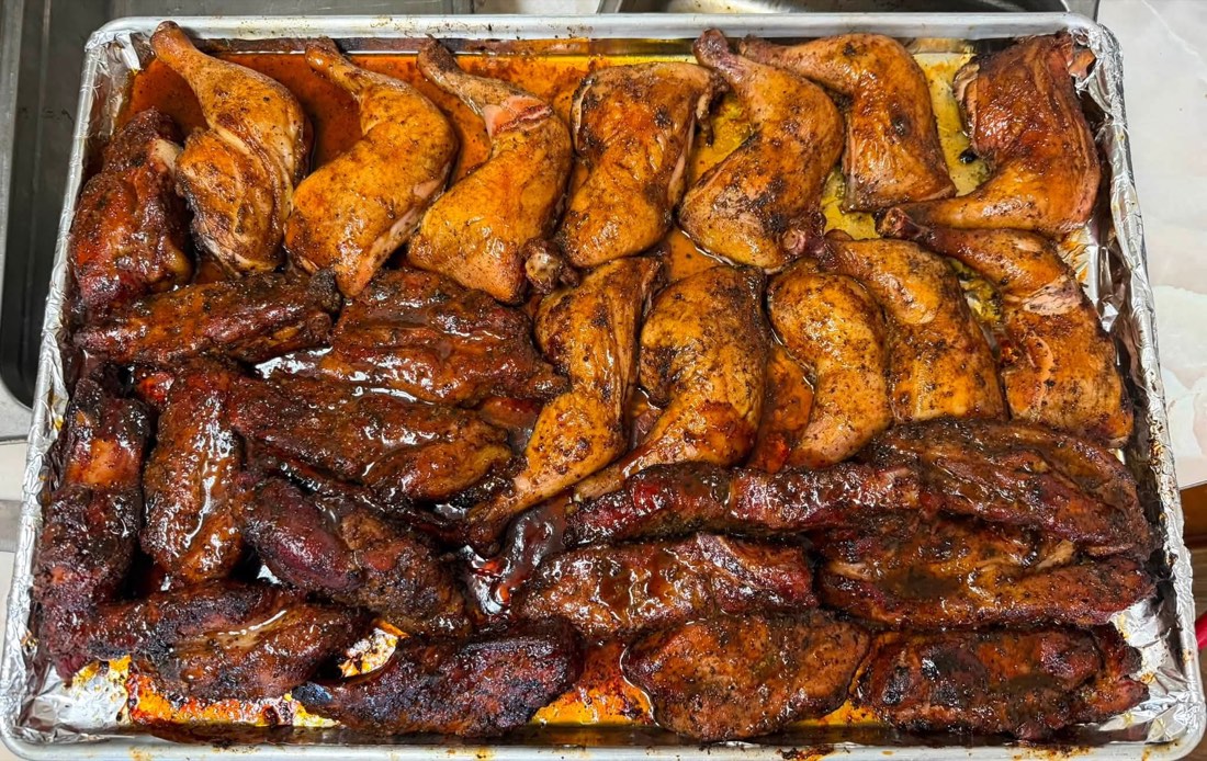 Large catering tray with brisket, ribs, sausage links, and chicken leg quarters
