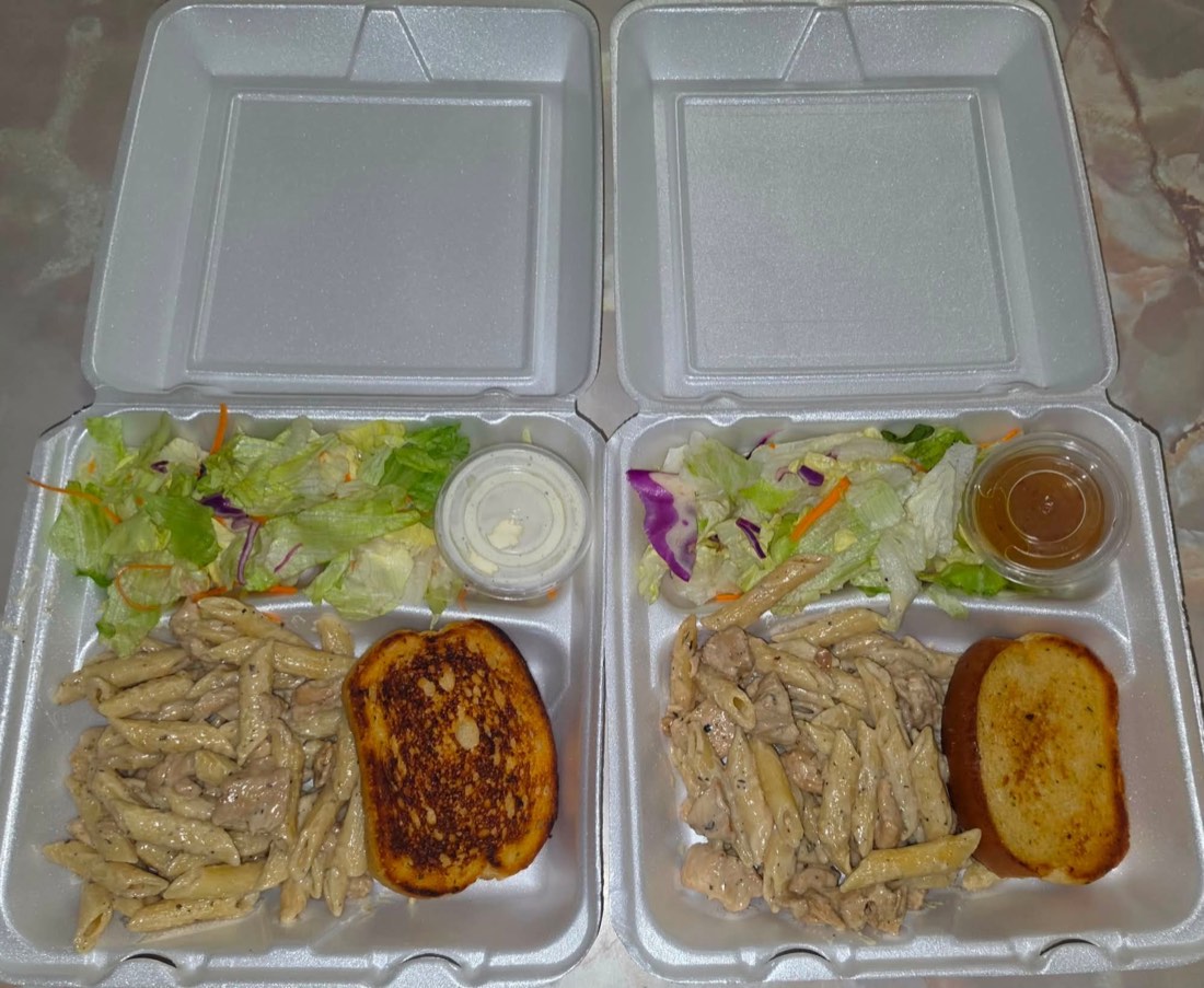 Full barbecue plate with brisket, sausage, chicken, ribs, beans, rice, potato salad, bread, pickles, and onions
