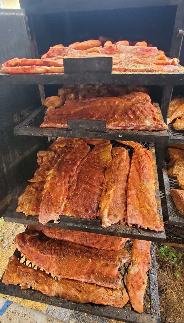 Seasoned racks of ribs arranged on shelves inside a smoker