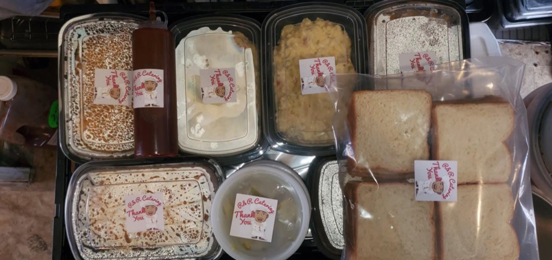 Packaged catering foods, bread, and sauce arranged with R&R thank-you labels