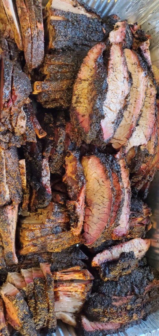 Tray piled with sliced brisket showing a seasoned bark and smoke ring
