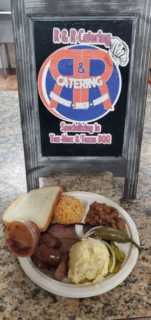 Barbecue plate with brisket, sausage, beans, Spanish rice, potato salad, bread, pickles, and sauce
