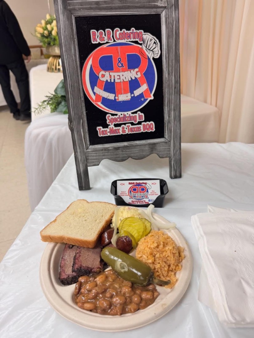 Brisket and sausage plate with beans, Spanish rice, potato salad, bread, pickles, and onions beside an R&R display
