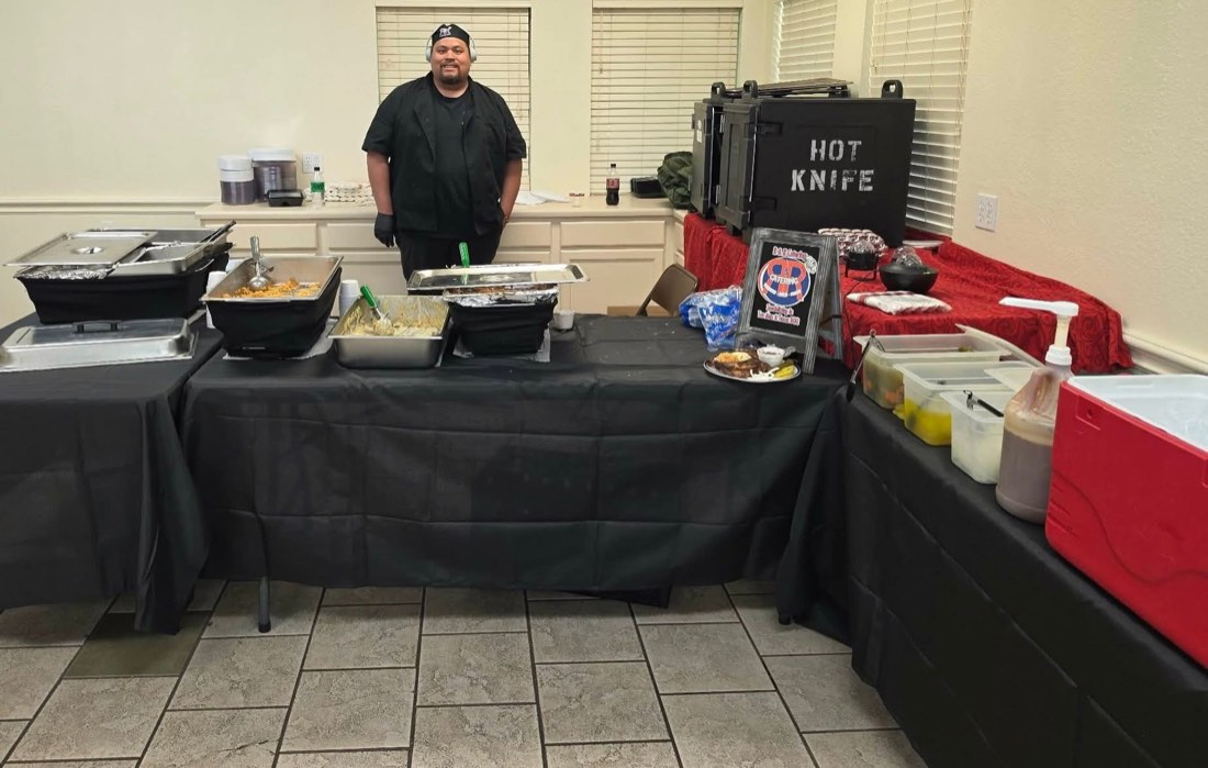 R&R Catering team member standing behind an indoor buffet and serving station