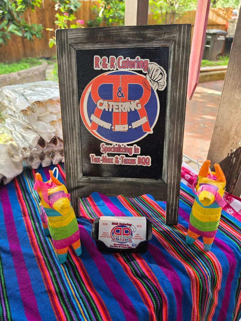 R&R Catering sign and business cards displayed on a colorful striped table with small decorative figures