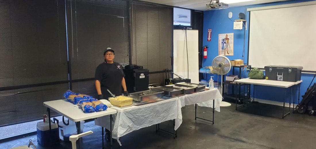 Indoor catering buffet with chafing dishes, bread, and a team member ready to serve